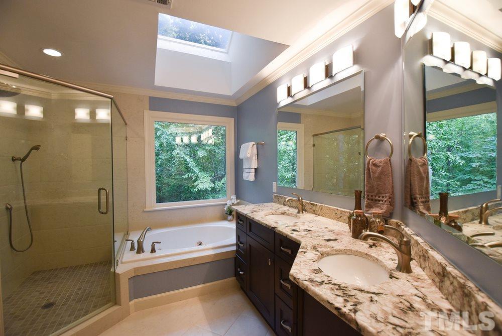 9004 Enfield Court Raleigh, NC 27615 - Photo 19 of 30 Updated Master Bath w/tile flr, granite vanity w/double sinks, jetted tub, lg tiled corner shower, crown molding, skylight & modern light fixtures.