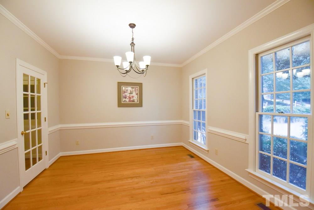 9004 Enfield Court Raleigh, NC 27615 - Photo 4 of 30 Formal Dining Rm w/hardwood flr, crown/chair rail molding, bronze iron light fixture & glass door to Kitchen.