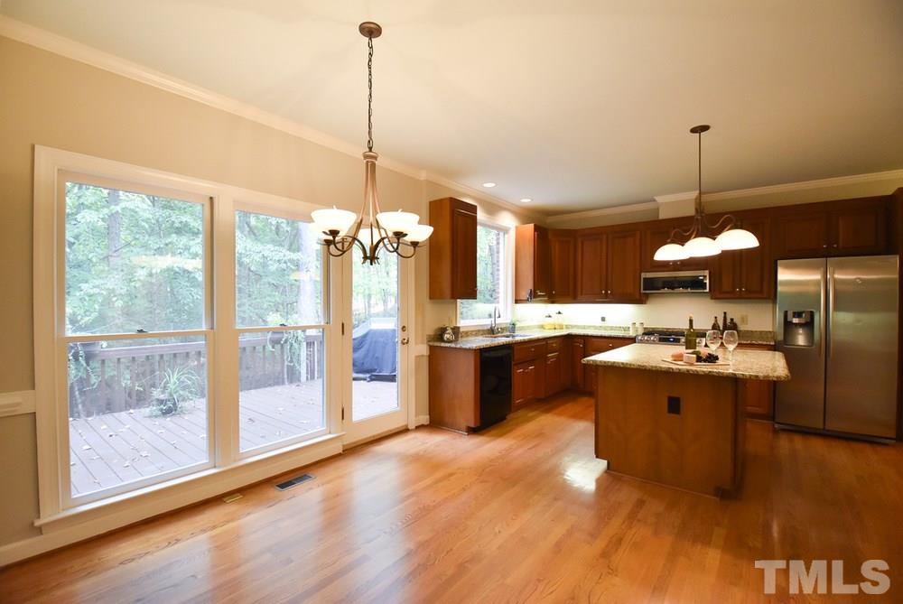 9004 Enfield Court Raleigh, NC 27615 - Photo 10 of 30 Bright Kitchen w/hardwood flr/crown/chair rail/lots of tall cherry cabinets/under-cabinet lighting/granite ctrs/subway tile backsplash/SS appliances (5-burner gas range/MW)/eat-at island/lg pantry & sunny Bfast area w/lg windows & door to Deck.