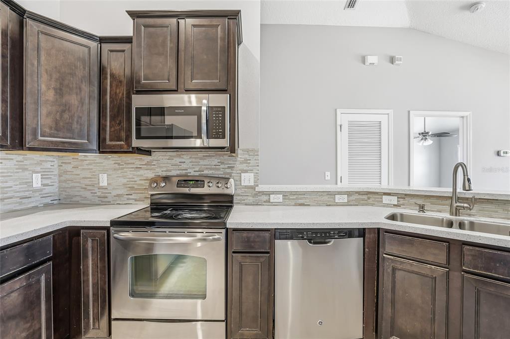 5723 Kingletsound Lithia, FL 33547 - Photo 15 of 33 a kitchen with stainless steel appliances granite countertop a stove microwave and sink