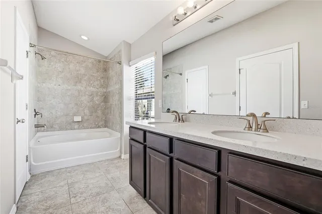 a bathroom with a tub sink double vanity granite and a bathtub