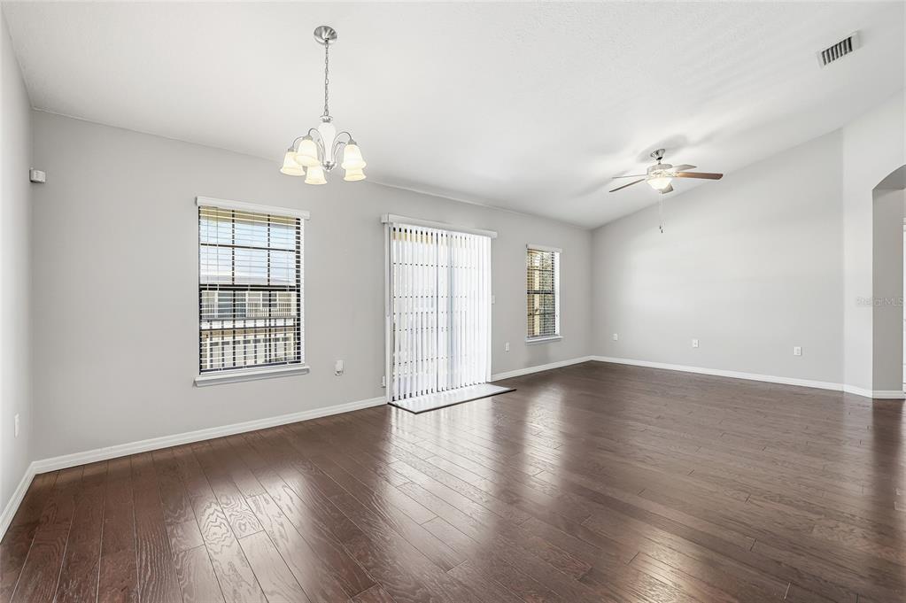 5723 Kingletsound Lithia, FL 33547 - Photo 5 of 33 an empty room with wooden floor chandelier fan and windows