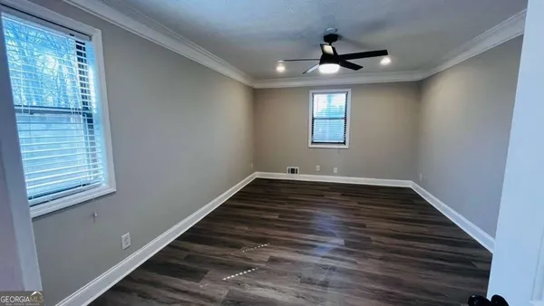 a view of an empty room with wooden floor and a window