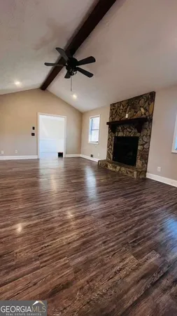 a view of an empty room with wooden floor and a ceiling fan
