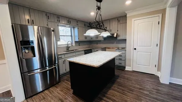 a kitchen with stainless steel appliances granite countertop a refrigerator a sink dishwasher a stove and a refrigerator