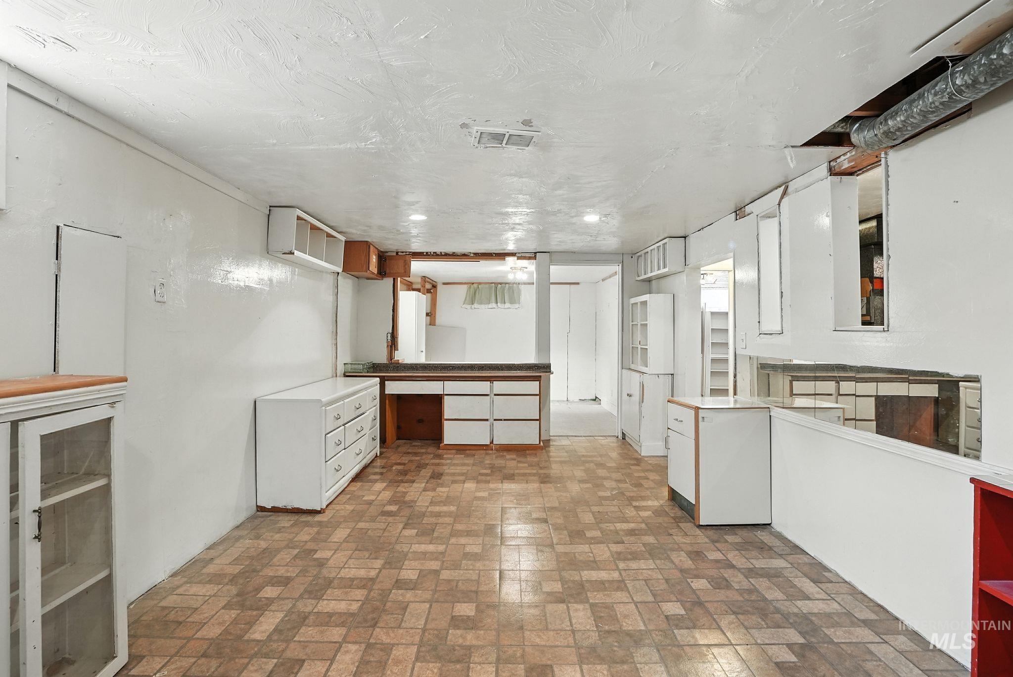 3506 10th Street Lewiston, ID 83501 - Photo 25 of 40 Kitchen with brick patterned flooring, open shelves, brown cabinetry, a textured ceiling, and white cabinets