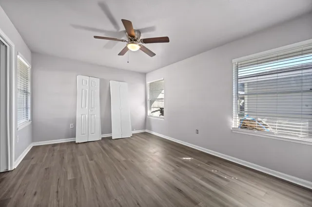 a view of an empty room with wooden floor and a window