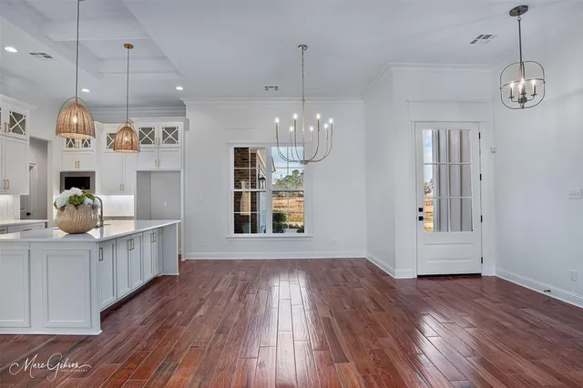 a hallway with a dining table wooden floor and chandelier