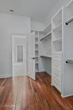 a view of an empty room with wooden floor and closet