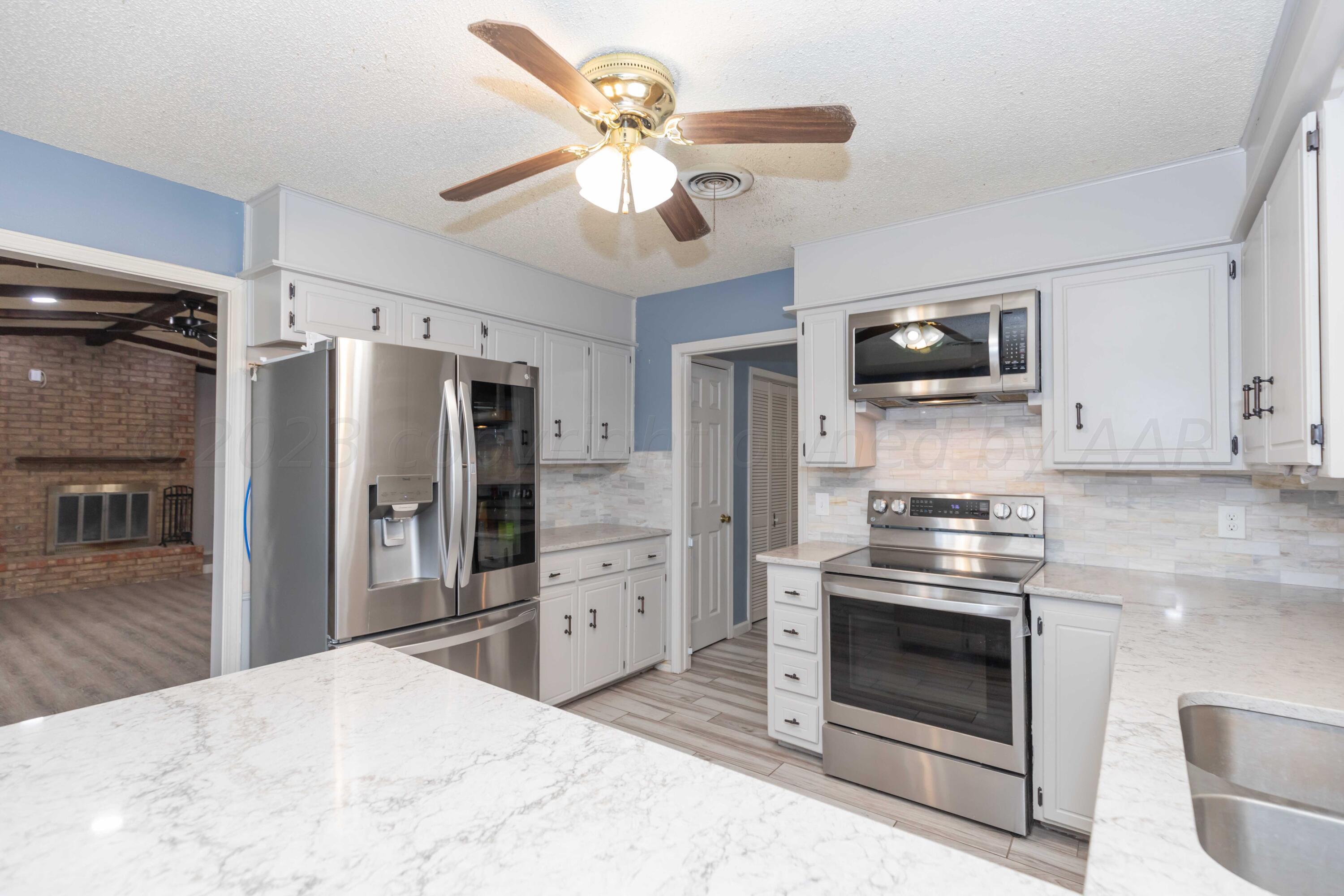 7110 Gainsborough Road Amarillo, TX 79106 - Photo 11 of 52 a kitchen with stainless steel appliances granite countertop a stove refrigerator and microwave