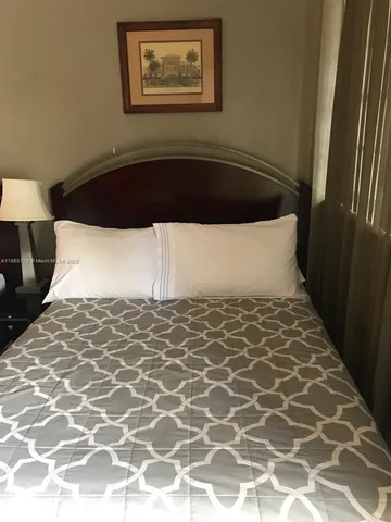 a white bed in a bedroom next to a lamp