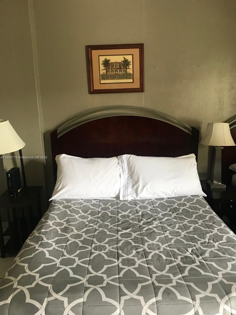 26 Diplomat Parkway, Unit 2233 Hallandale Beach, FL 33009 - Photo 4 of 7 a white bed in a bedroom next to a lamp