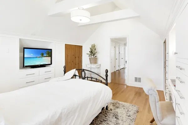 a bedroom with a bed and a flat tv screen on dresser