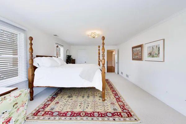 a bed sitting in a bedroom next to a window with a rug