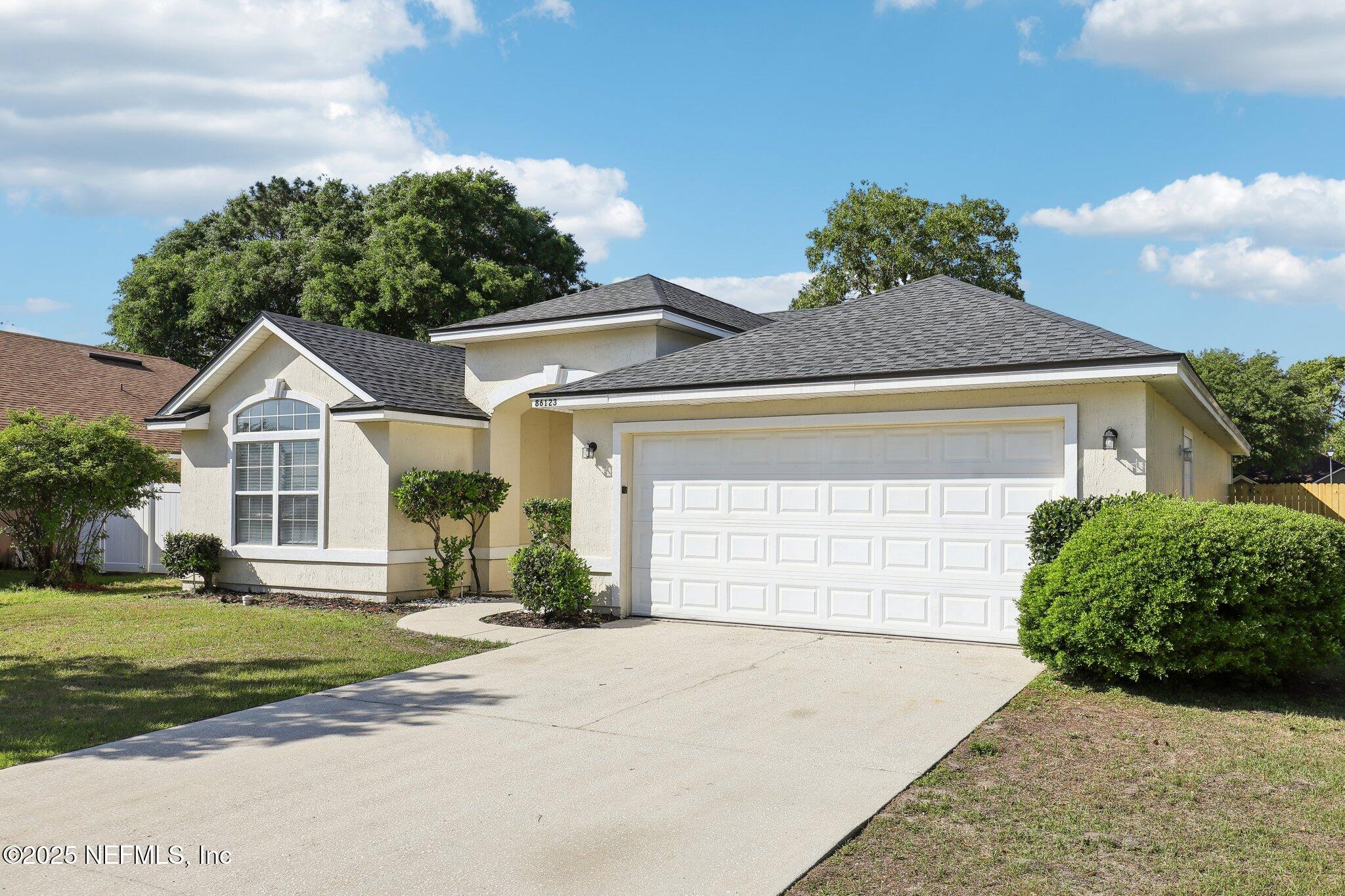 86123 Red Holly Place Yulee, FL 32097 - Photo 2 of 36 a front view of a house with a yard and garage