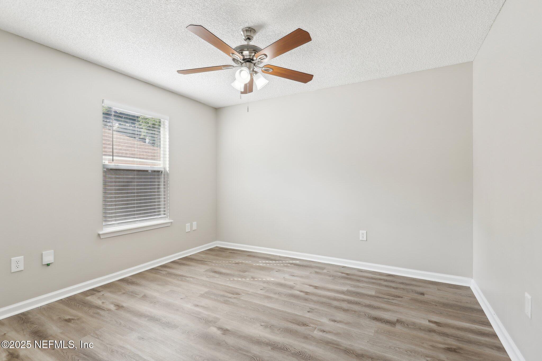86123 Red Holly Place Yulee, FL 32097 - Photo 23 of 36 an empty room with wooden floor fan and windows
