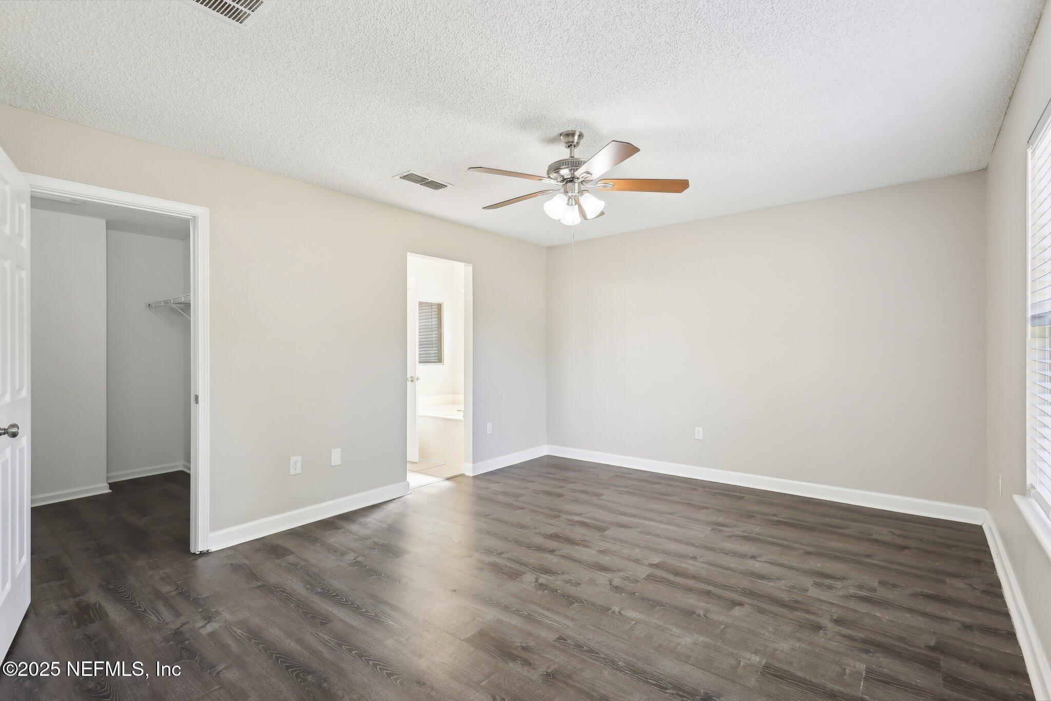 86123 Red Holly Place Yulee, FL 32097 - Photo 25 of 36 an empty room with wooden floor chandelier fan and windows
