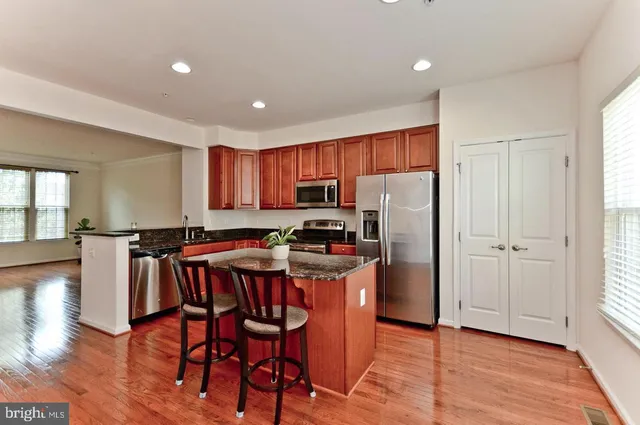 a kitchen with stainless steel appliances granite countertop a refrigerator a stove top oven a sink dishwasher and white cabinets with wooden floor