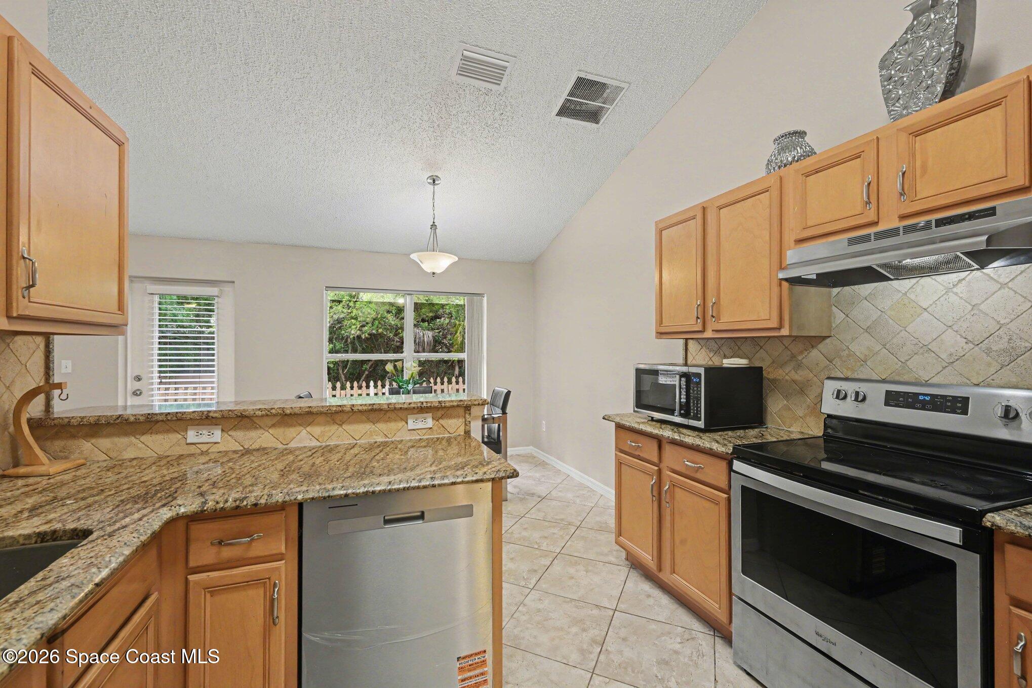 558 Barber Street Sebastian, FL 32958 - Photo 11 of 25 a kitchen with granite countertop a sink stainless steel appliances white cabinets and a window
