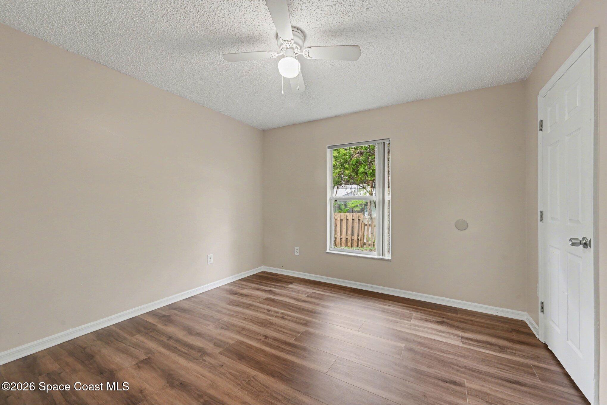 558 Barber Street Sebastian, FL 32958 - Photo 17 of 25 an empty room with wooden floor ceiling fan and windows