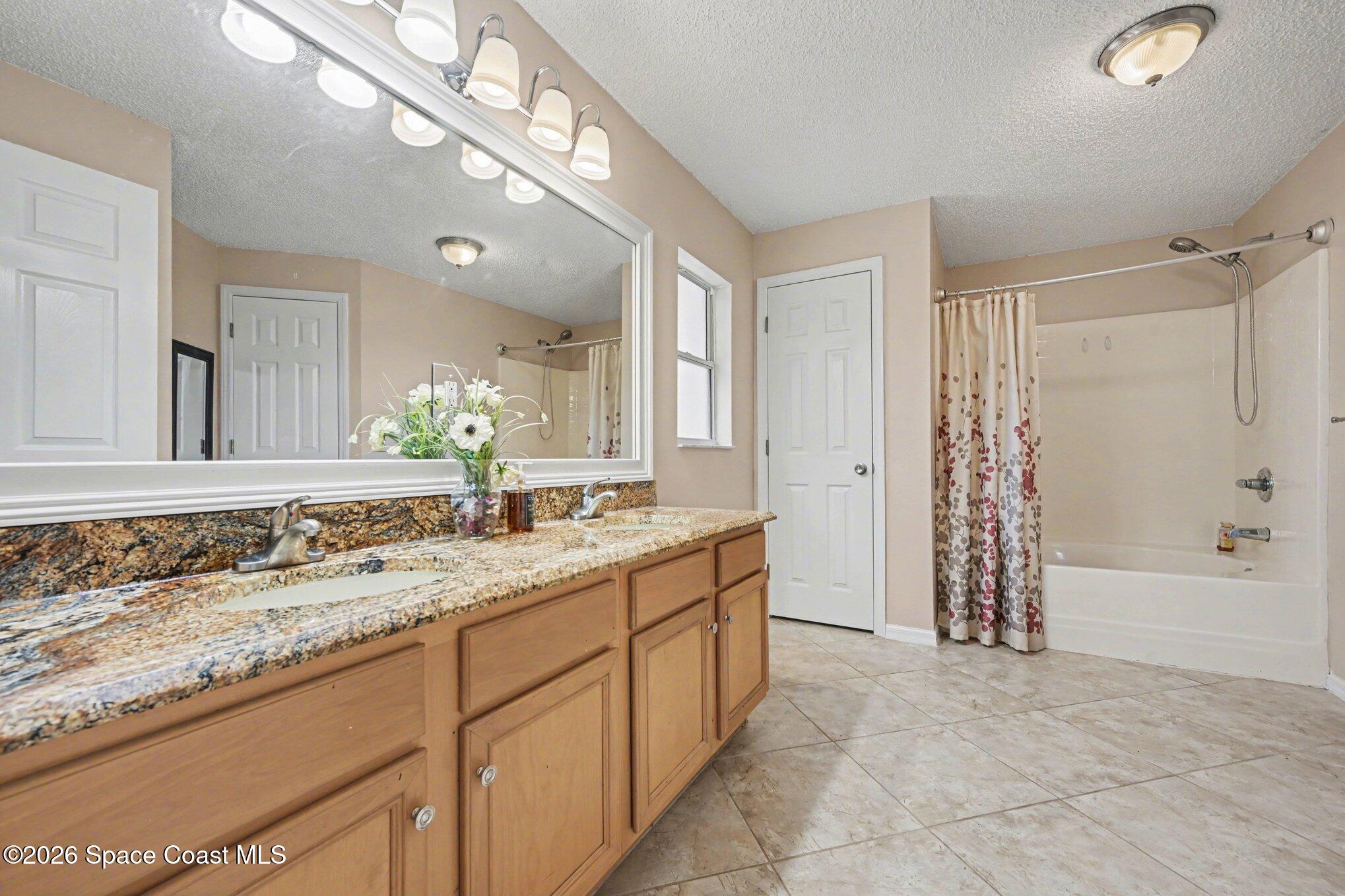 558 Barber Street Sebastian, FL 32958 - Photo 20 of 25 a bathroom with a granite countertop sink a large mirror and a bathtub