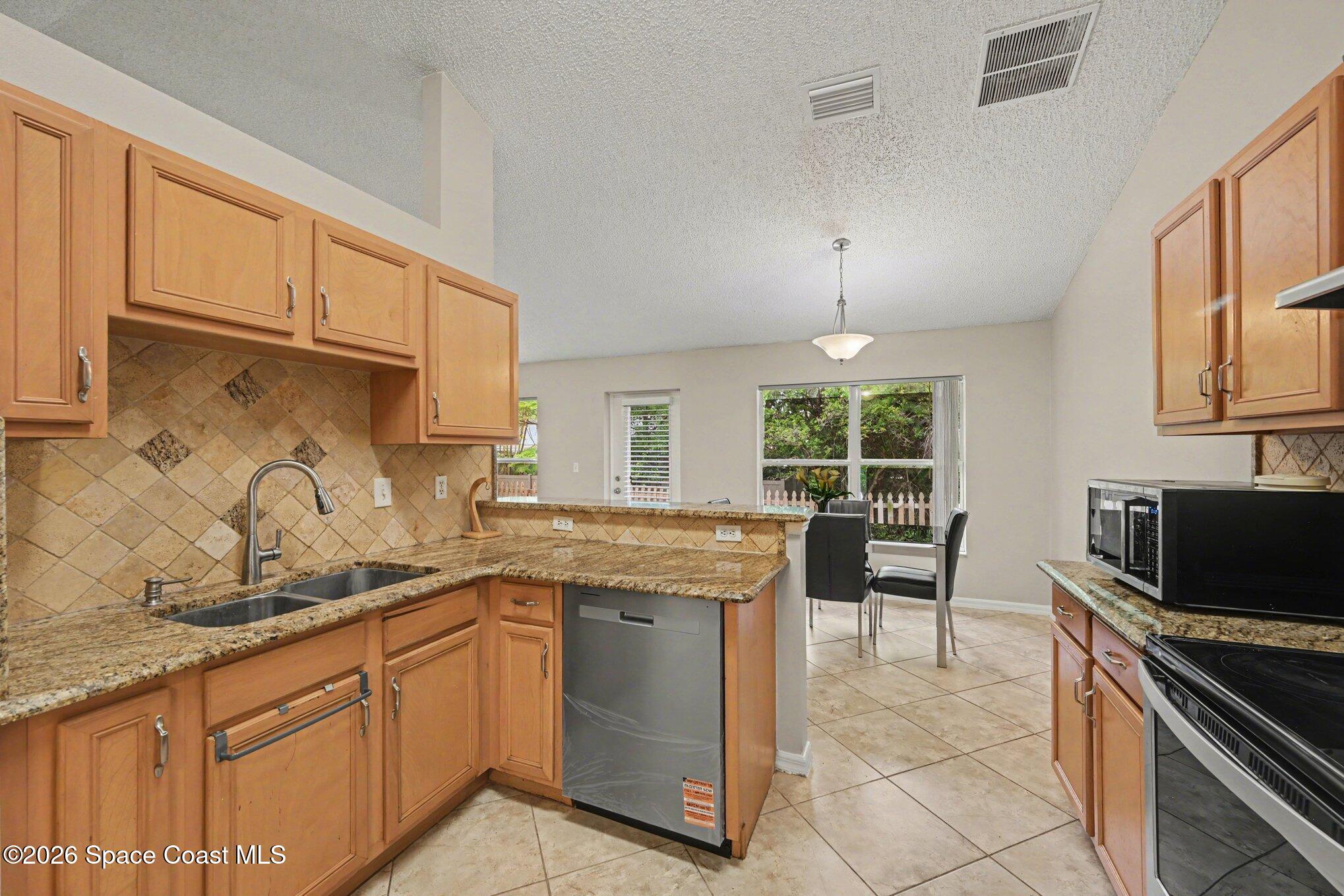558 Barber Street Sebastian, FL 32958 - Photo 10 of 25 a kitchen with stainless steel appliances granite countertop a stove a sink and a microwave
