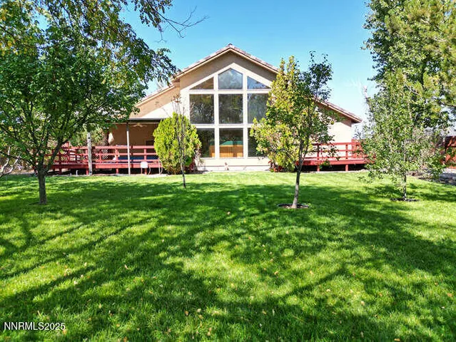 a view of a house with a big yard and large trees