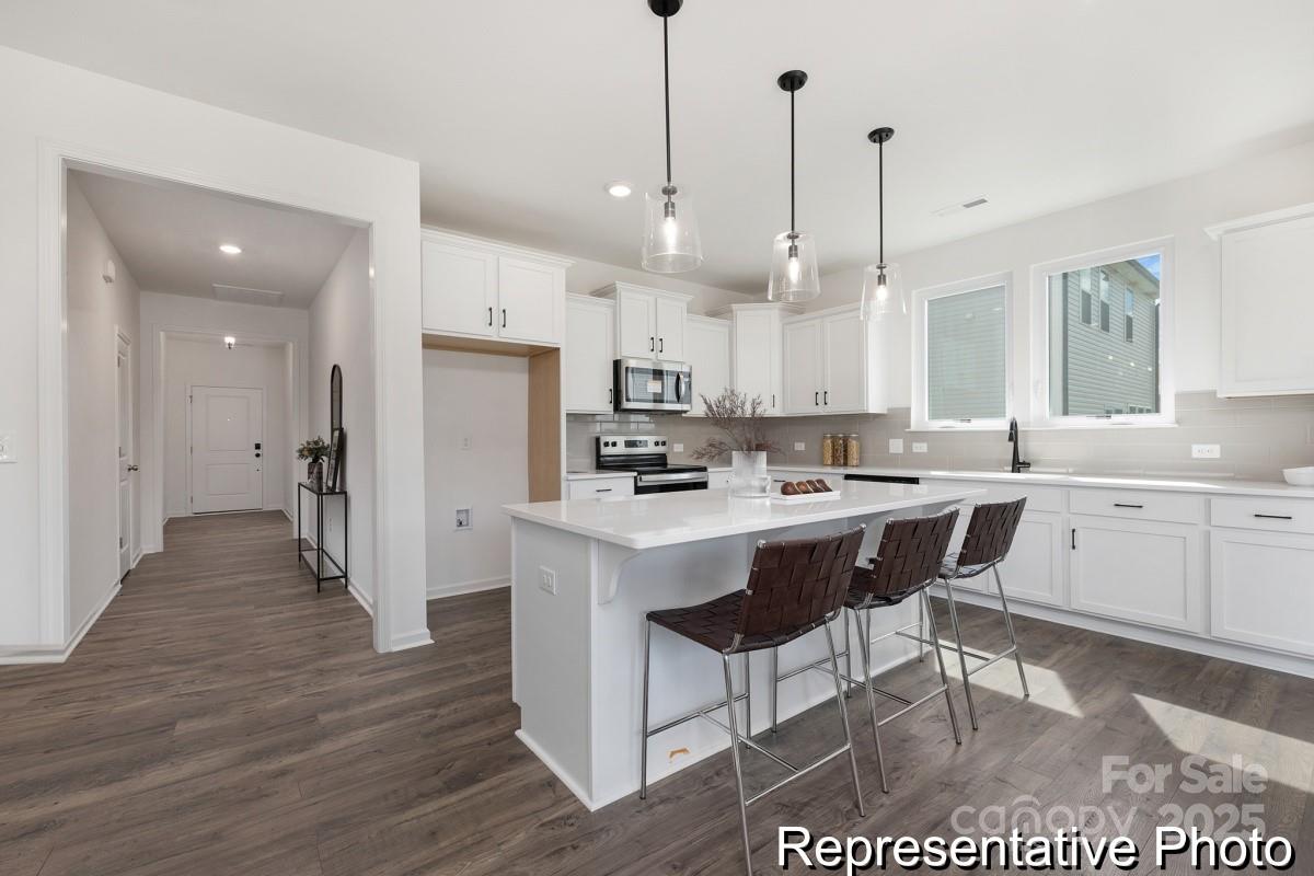 104 Soft Breeze Bend, Unit 160B Locust, NC 28097 - Photo 4 of 22 a kitchen with stainless steel appliances kitchen island granite countertop a sink a stove a refrigerator and white cabinets with wooden floor
