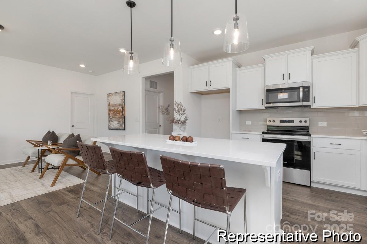 104 Soft Breeze Bend, Unit 160B Locust, NC 28097 - Photo 6 of 22 a kitchen with stainless steel appliances kitchen island granite countertop a sink a stove a dining table and chairs