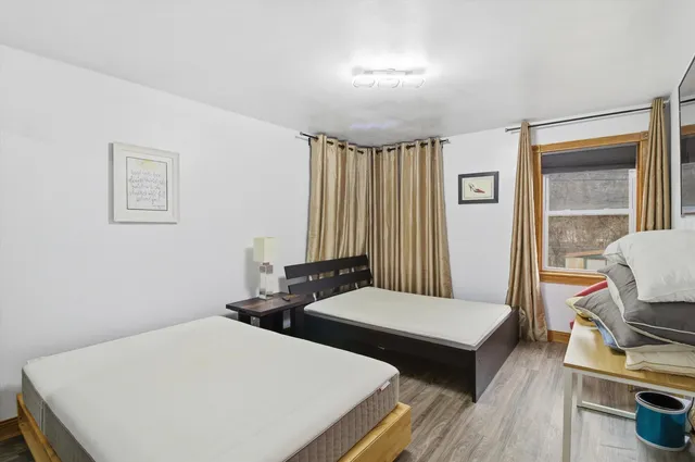 a bedroom with two beds and wooden floor