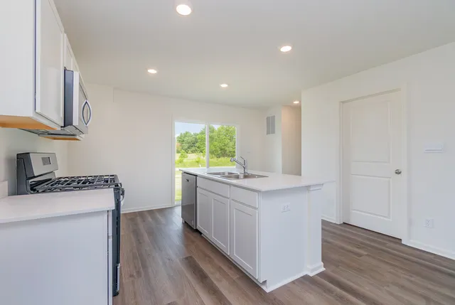 a kitchen with stainless steel appliances granite countertop a stove a sink and a refrigerator