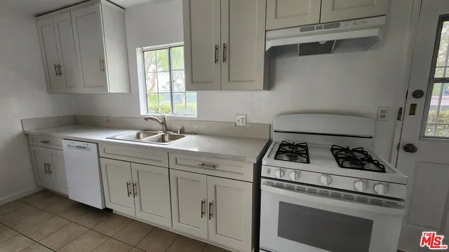 a kitchen with cabinets appliances a sink and a window