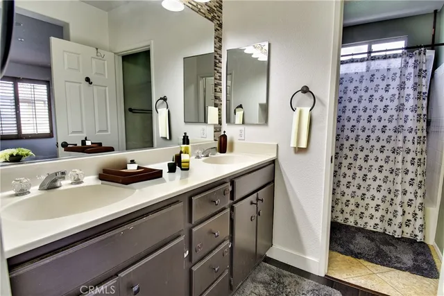 a bathroom with a double vanity sink a mirror a and a shower