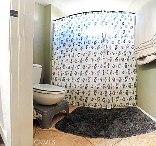 a bathroom with a toilet and a shower curtain
