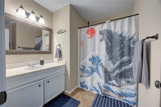 a bathroom with a granite countertop sink a mirror and shower