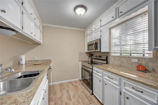 a kitchen with granite countertop a sink stainless steel appliances and cabinets