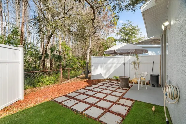 a backyard of a house with table and chairs under an umbrella