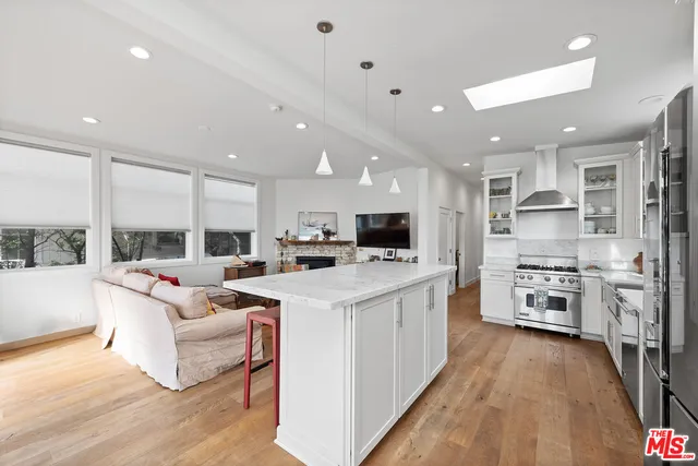 a kitchen with stainless steel appliances white cabinets a stove a sink and a wooden floors