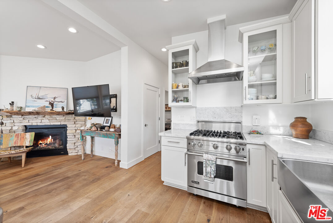 29500 Heathercliff Road, Unit 16 Malibu, CA 90265 - Photo 12 of 25 a kitchen with stainless steel appliances white cabinets a stove a sink and a wooden floors