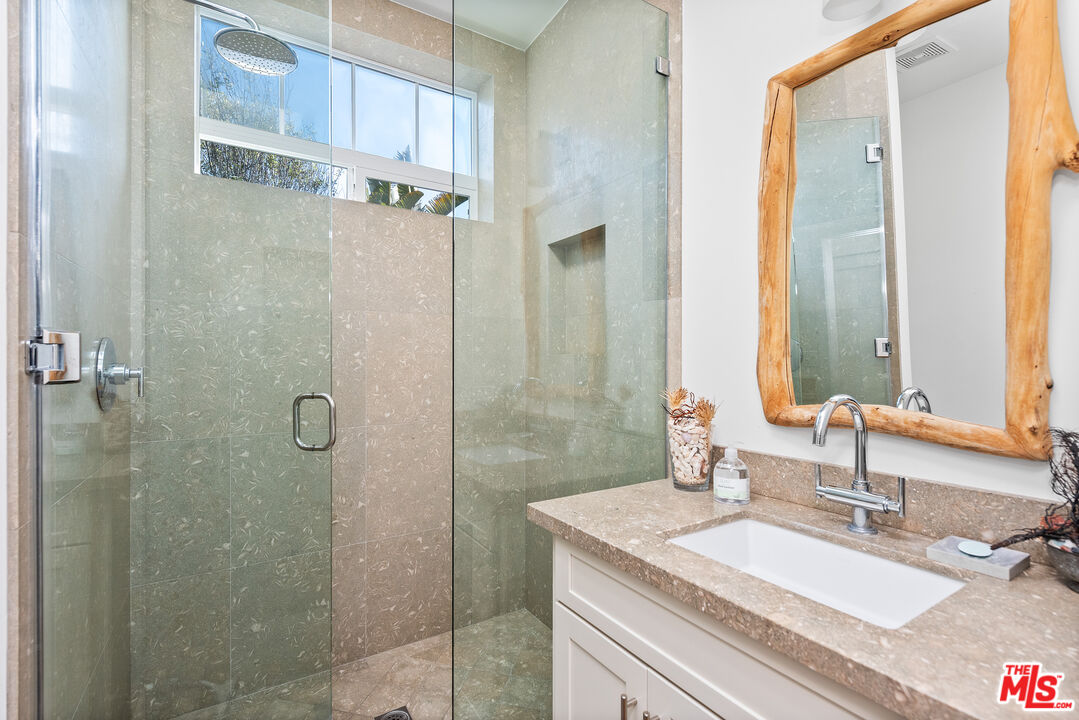 29500 Heathercliff Road, Unit 16 Malibu, CA 90265 - Photo 16 of 25 a bathroom with a granite countertop sink a mirror and a shower