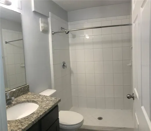a bathroom with a granite countertop bathtub shower sink vanity and toilet