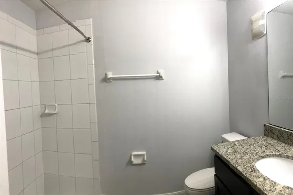 a bathroom with a granite countertop sink and a toilet
