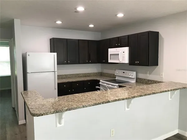 a kitchen with stainless steel appliances granite countertop a sink refrigerator and microwave