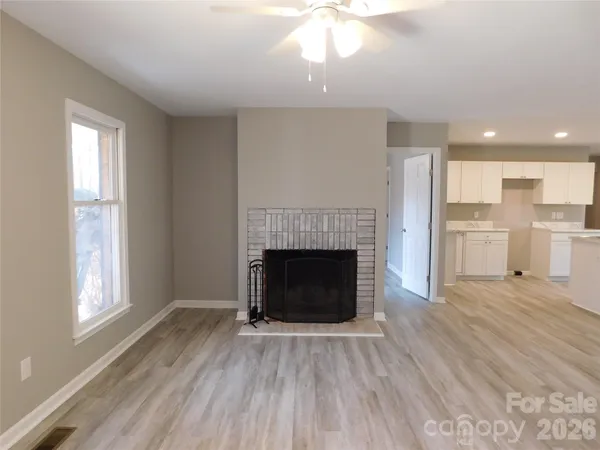 a view of a livingroom with a fireplace wooden floor and windows