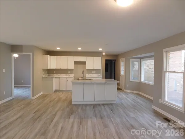 a open kitchen with white cabinets and wooden floor