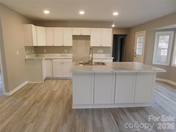 a kitchen with kitchen island white cabinets and sink
