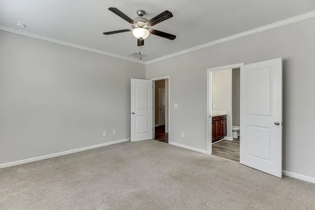 an empty room with chandelier fan and windows