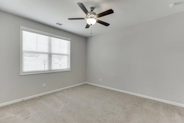 an empty room with a window and a fan