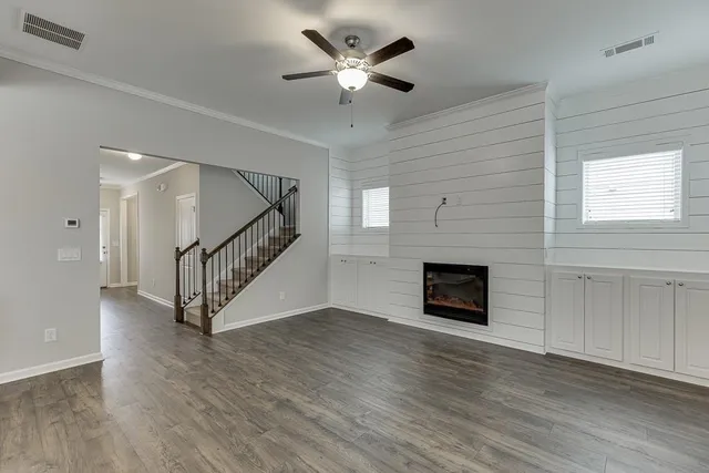 a view of an empty room with wooden floor a fireplace and a window
