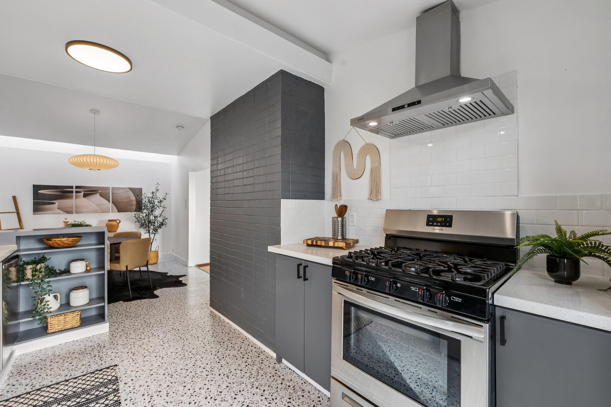 1024 Miller Avenue Berkeley, CA 94708 - Photo 22 of 60 Kitchen featuring gas range, wall chimney range hood, dark aggregate flooring, gray cabinetry, and light stone counters